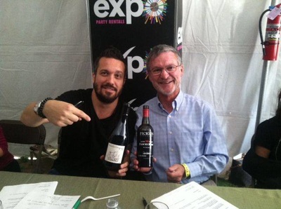 Celebrity Chef Fabio Viviani points to a bottle he's holding of Ficklin Vineyards Liga da Caravel Tawny Port with a smile while Peter Ficklin sits beside him.