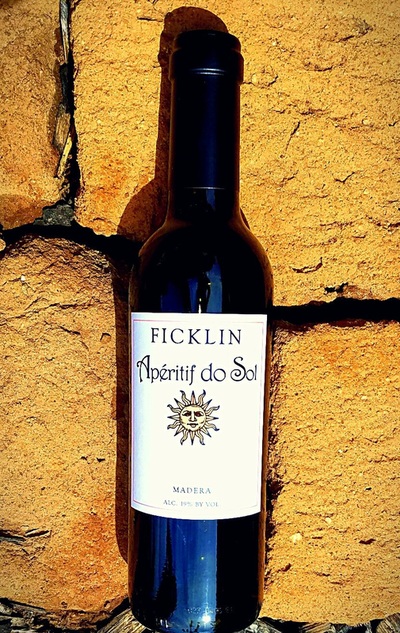 A 375 ml bottle of Aperitif do Sol laying on 4 Adobe bricks in the sun.