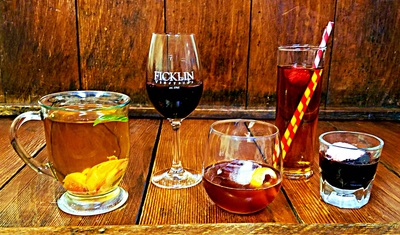 An assortment of glass styles with various chilled Ficklin Ports, some with ice, straws, and fruit garnishes.
